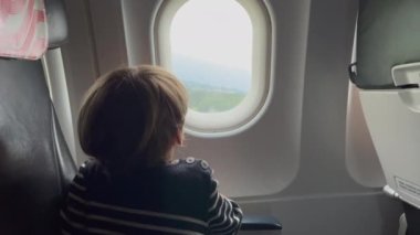 Child looking at airplane window during take off. Flight flying departure