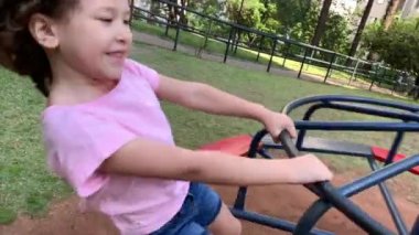 Small girls playing in playground carousel roundabout in motion