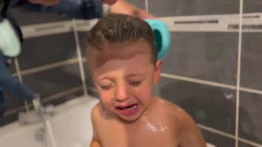 Crying child taking bath. Tearful little boy cries while bathing in shower routine. Upset kid at bath tub