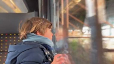 Child traveling by train. Little boy staring at landscape pass by in high speed transportation. Kid in moving train