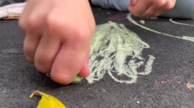 Closeup child hand drawing in street with chalk
