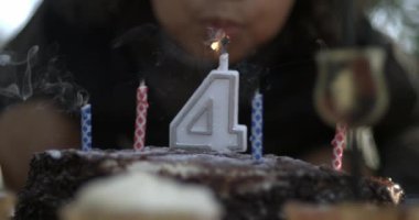 Çocuk çikolatalı pastaya mum üflüyor, 4 yaşında, doğum günü kutlaması, yüksek hızlı 800 fp.