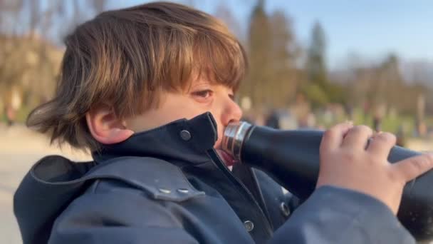 公園の屋外でボトルから飲む喉の渇き少年 顔を閉じて自分自身を水分補給 — ストック動画