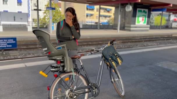 電車が自転車で到着するのを待っているプラットフォームに立っている疲れた女性 朝から通勤する人 — ストック動画