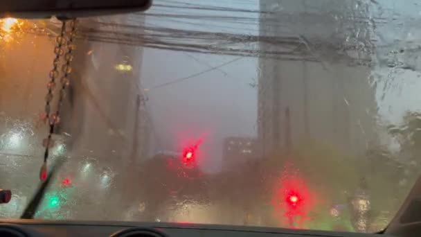 車のフロントガラスの中に雨を注ぐ 市内の雨の夜の窓を注ぐ中で赤い光を待っている乗客 — ストック動画