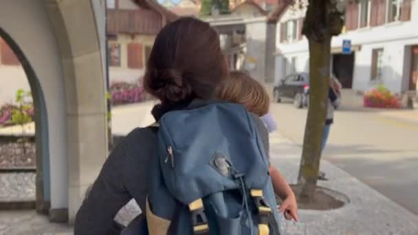 Back Mother Carrying Child Arms While Walking European Street Sunny — Vídeos de Stock
