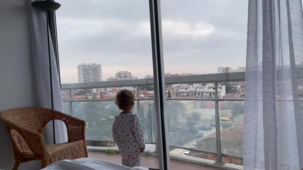 Βρέφος Παιδί Στέκεται Από Παράθυρο Του Ξενοδοχείου Κοιτάζοντας Την Πόλη — Αρχείο Βίντεο
