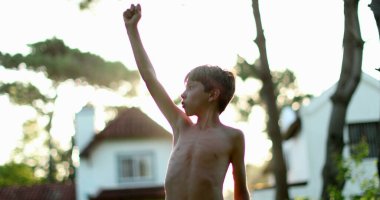 Child in victory stand raising fist in the air celebrating achievement and success with arm raised to the sky