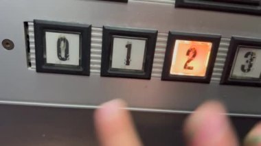Child hand pressing old elevator buttons.