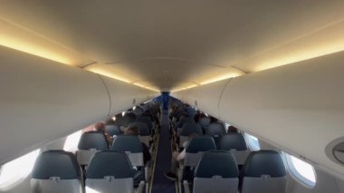  Plane cabin seen from the back. Passengers seated inside airplane