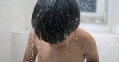 Su damlacıkları süper yavaş çekimde çocuk vücuduna düşüyor. 1000 fps 'lik genç çocuk banyosu zamanı.