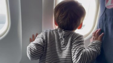 Back of child leaning on plane window. Little boy passenger traveling.