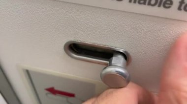 Hand locking airplane bathroom door lock. Closeup finer hands occupied sign inside plane cabin