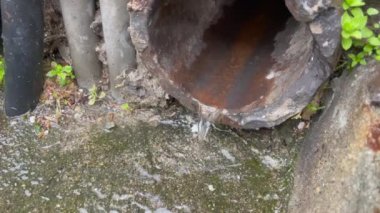  Droplets falling in sewage system. Aged pipe closeup in street.