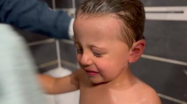 Parent drying child face after bath. Family lifestyle night routine before bed. Mother dries little boy with towel.