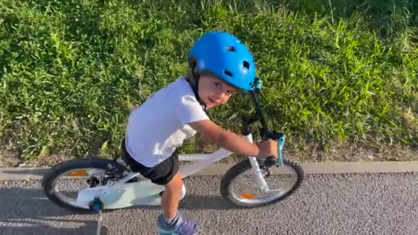 保護ヘルメットと1つのアクティブなかわいい男の子の自転車に乗って カメラの笑顔を見て — ストック動画