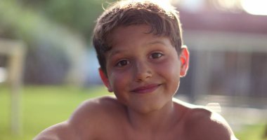 Handsome child boy smiling to camera in outdoor backyard garden. Happy kid portrait