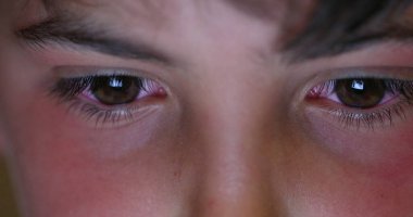 Kid eyes staring at screen light at night. Boy addicted to electronic watching phone or tablet device