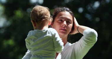 Anne şefkati ve sevgi dolu bebek dışarıda, gün ışığında.