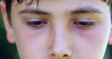Pensive child close-up eyes thinking. Thoughtful young boy wondering