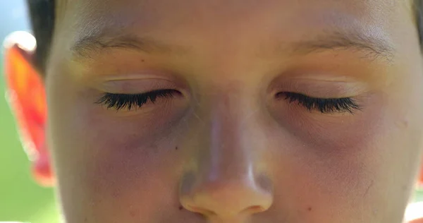 Kid face close-up closing eyes in meditation. Child boy opening eyes smiling to camera, macro closeup