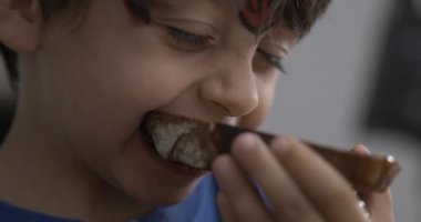 Küçük bir çocuk tost ekmeğinden bir ısırık alıyor, çocuk ağzı kapanıyor süper yavaş çekimde karbonhidrat yiyor 800 fps hız rampası
