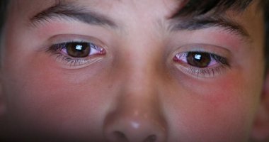 Macro close-up boy eyes staring at tablet screen device, browsing online content, watching movie