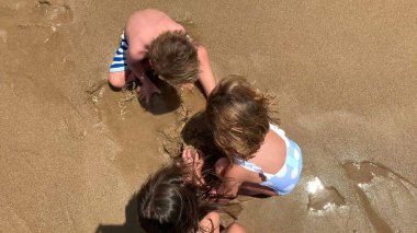 Kumsalda kumla oynayan çocuklar, deniz kıyısında yukarıdan görülen çocuklar.