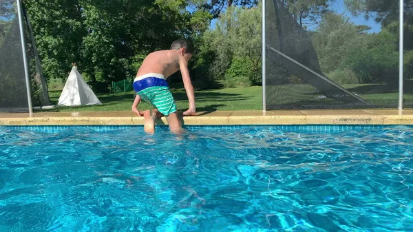 男の子プールサイドから体を持ち上げる 子供はプールの水から出る — ストック写真