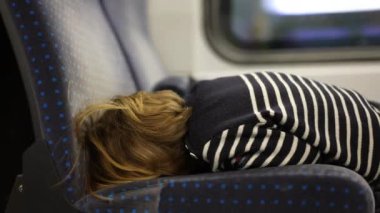 Seyahat sırasında yapacak bir şeyi olmayan, tren koltuğuna yaslanmış sıkılmış bir çocuğun sırtı.