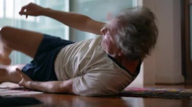 Kıdemli adam sabah egzersizi sırasında yerden kalkıyor. Nilüfer pozisyonunda oturan yaşlı beyaz adam meditasyon yapmaya hazırlanıyor.