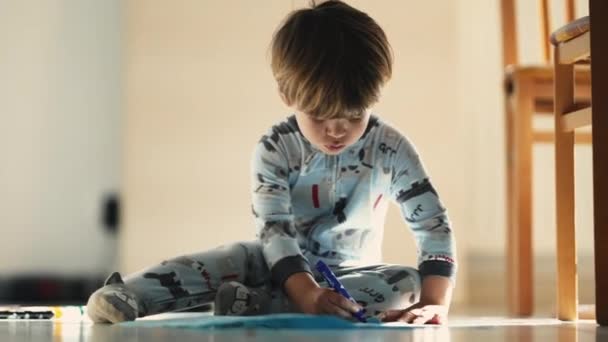 Sabah Yaratıcılığı Pijamalı Çocuk Yerde Mavi Kalemle Çizim Yapıyor — Stok video