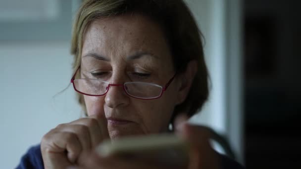 Пожилая Женщина Царапает Нос Лицо Чтении Контента Интернете Помощью Смартфона — стоковое видео