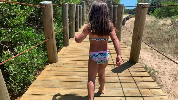 小女孩走在沙滩上的木径上 — 图库照片