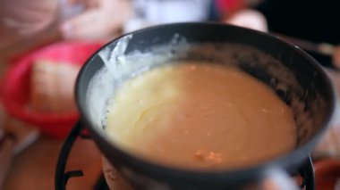 Fondü yakın çekim, sıcak tavada peynir, geleneksel kış İsviçre yemekleri.