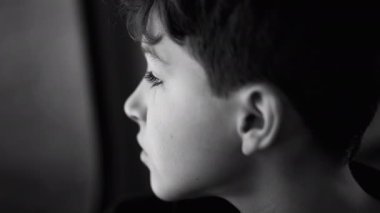 Depresyonda olan ergen bir erkek çocuk pencerenin önünde tefekkür ederek seyahat ediyor. Düşünceli çocuk profili yakın plan