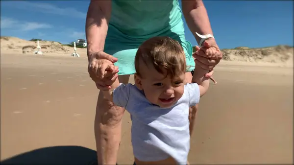 Grand-parent holding baby infant at beach