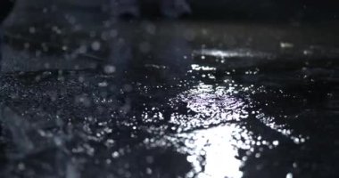 Sıvı su birikintisi, ışığın yanmasıyla yüksek çişli 800 fp yavaş çekimde, damlacıklar sıçrıyor.