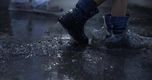 Close Regenlaarzen Wandelen Door Waterplassen Spetterende Druppels Overal Hoge Snelheid — Stockvideo
