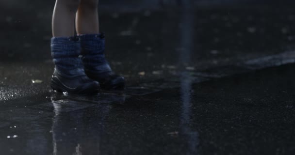 雨の日に歩道で立っているレインボットを身に着けている子供の足のクローズアップ ドロップセットは800 Fpsで高速カメラでキャプチャされた超遅い動きに落ちます — ストック動画