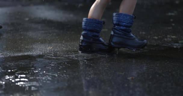 孩子的脚在外面的雨中走在城市街道的人行道上 水滴以超低的速度落下 用高速相机拍摄 下雨天 — 图库视频影像