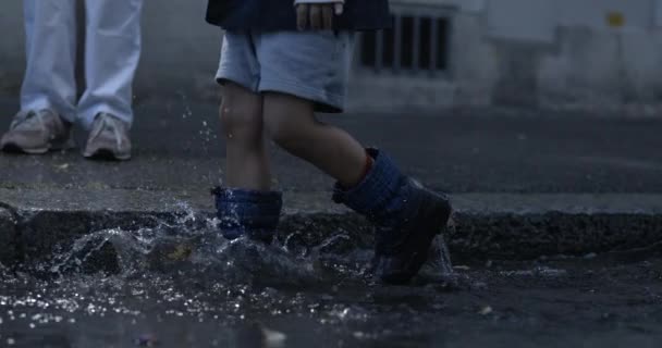 小孩的雨靴步法向空中喷射水花 用高速相机在人行道上以每秒800英尺的速度拍摄 — 图库视频影像