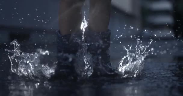 高速カメラで撮影された超スローモーションで楽しむ水プドルで空中にジャンプする雨のブーツを着用した子供のノスタルジックなシーン — ストック動画