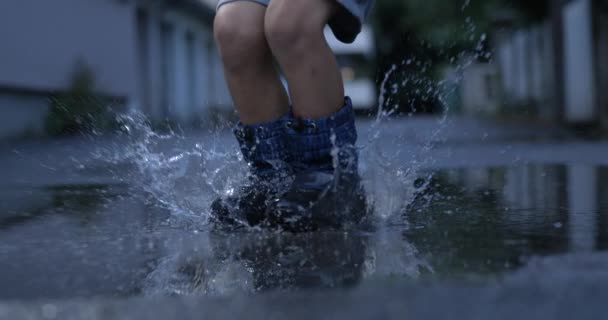 欢快的水花 穿着雨靴的孩子在跳跃进入灌篮的喜悦中狂欢 用高速相机慢动作拍摄 — 图库视频影像