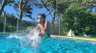 Yaz günü havuza atlayan ve koşan bir çocuk.