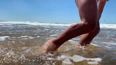 Çocuk plajda oynuyor. Kumsalda kumlara dokunan mutlu küçük kız