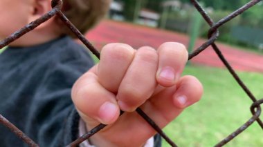Closeup of baby little hand holding fence