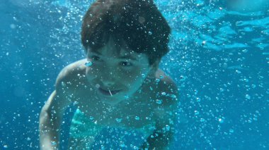 Mutlu çocuk güneşli bir günde havuzda yüzüyor.