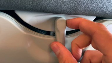 Koltuğun arkasına masa tepsisi koymak için el açma düğmesi. Görünür tepsi yerleştirilmiş, düğmeyi çeviren birinin eli.