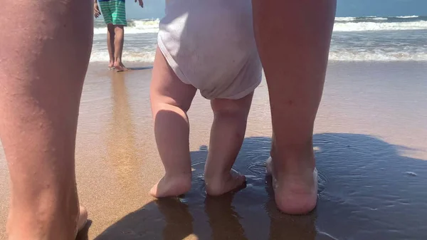 Infant feet and toes walking at sea shore beach
